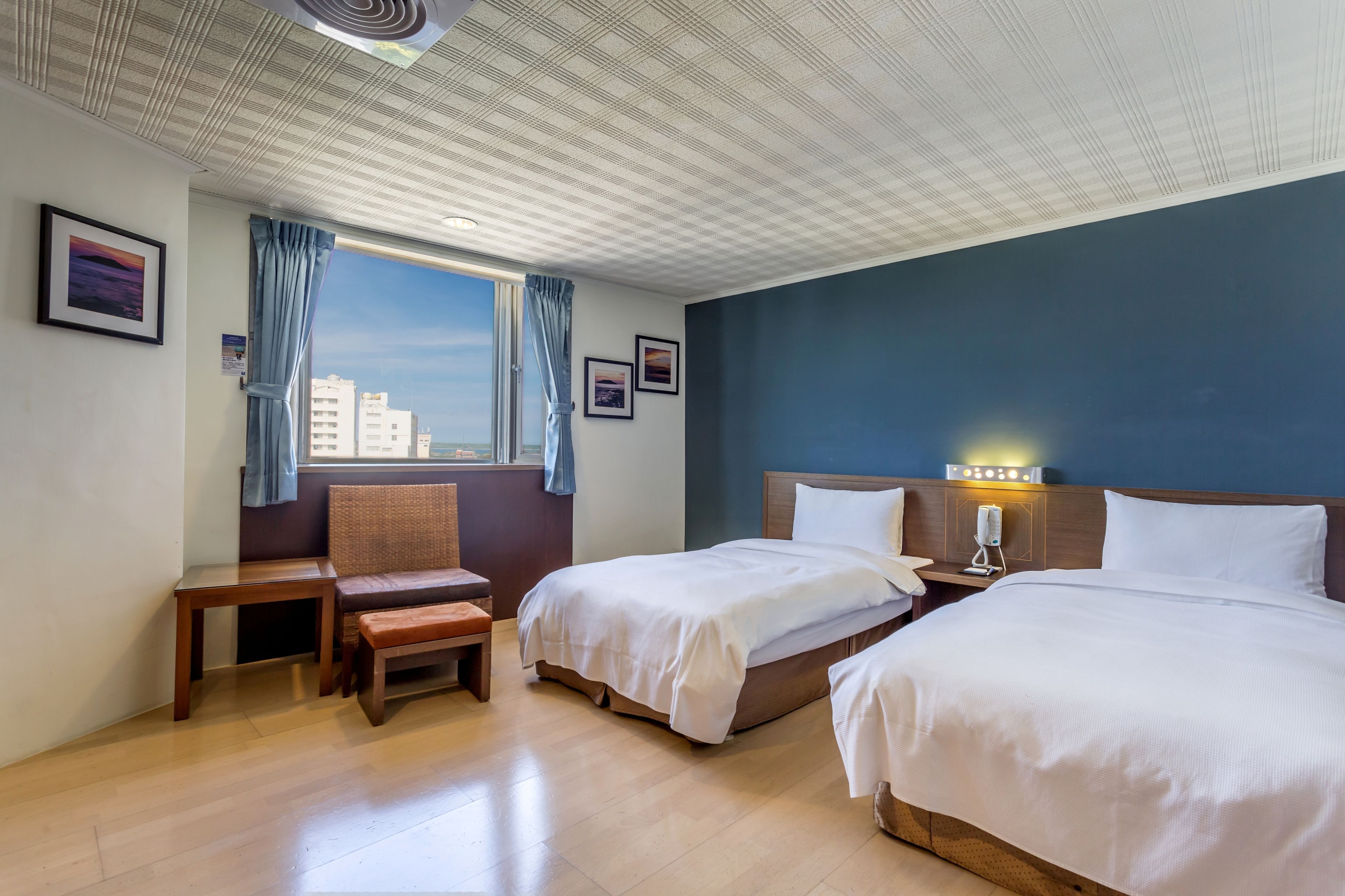 A hotel room with two beds, a desk, a chair, and a window with curtains.