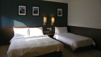 Habitación de hotel con dos camas, cabecero de madera, mesita de noche con teléfono y tres cuadros enmarcados en la pared.