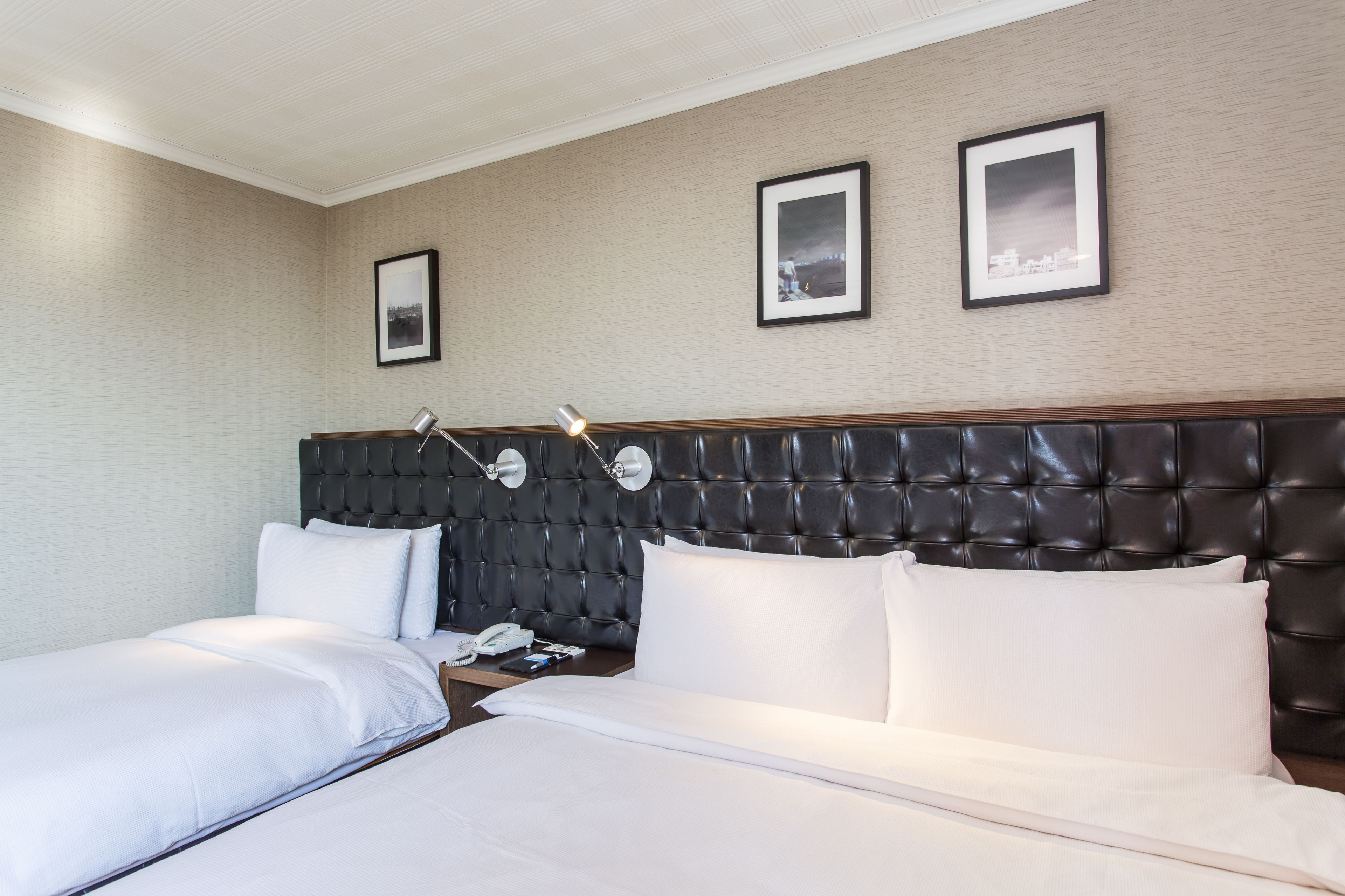 Une chambre d’hôtel avec un grand lit, deux tables de chevet, une tête de lit et deux tableaux encadrés au mur.