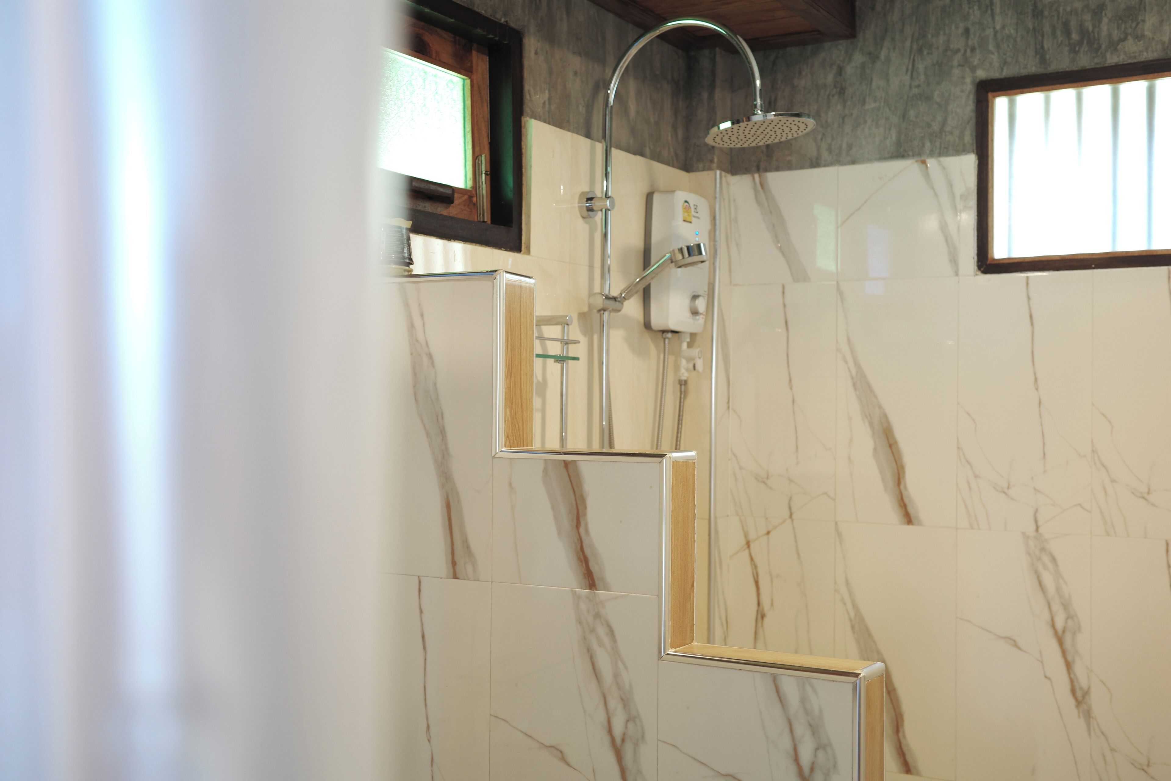 Un bagno moderno con doccia, piastrelle in marmo e specchio con cornice in legno.