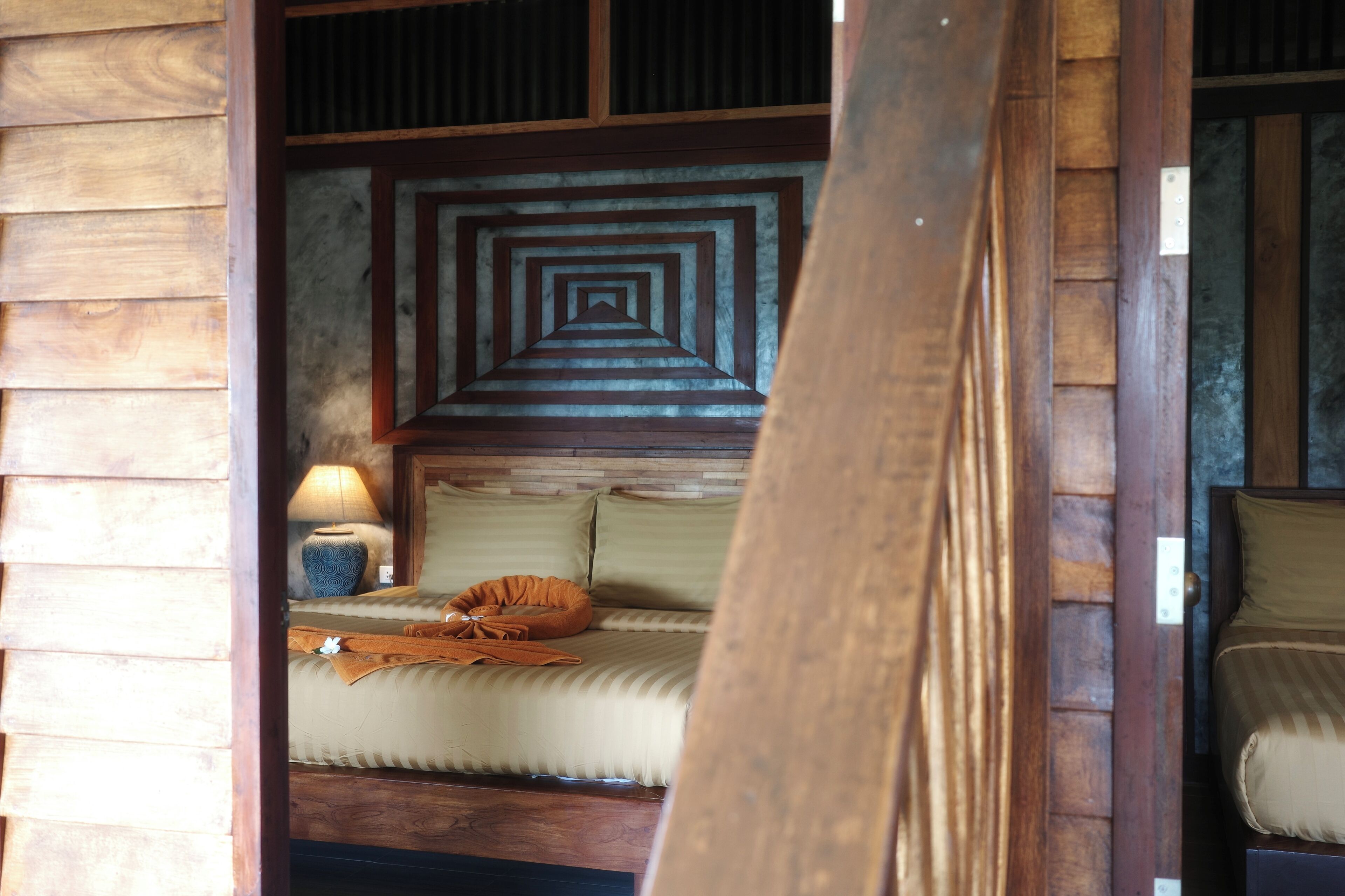 A wooden room with a bed, a nightstand, and a lamp.