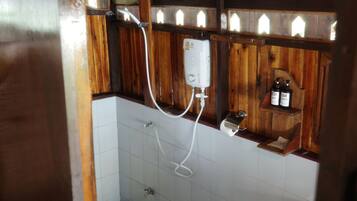 A bathroom with a wooden shower enclosure, a white tiled floor, and a shelf with toiletries.