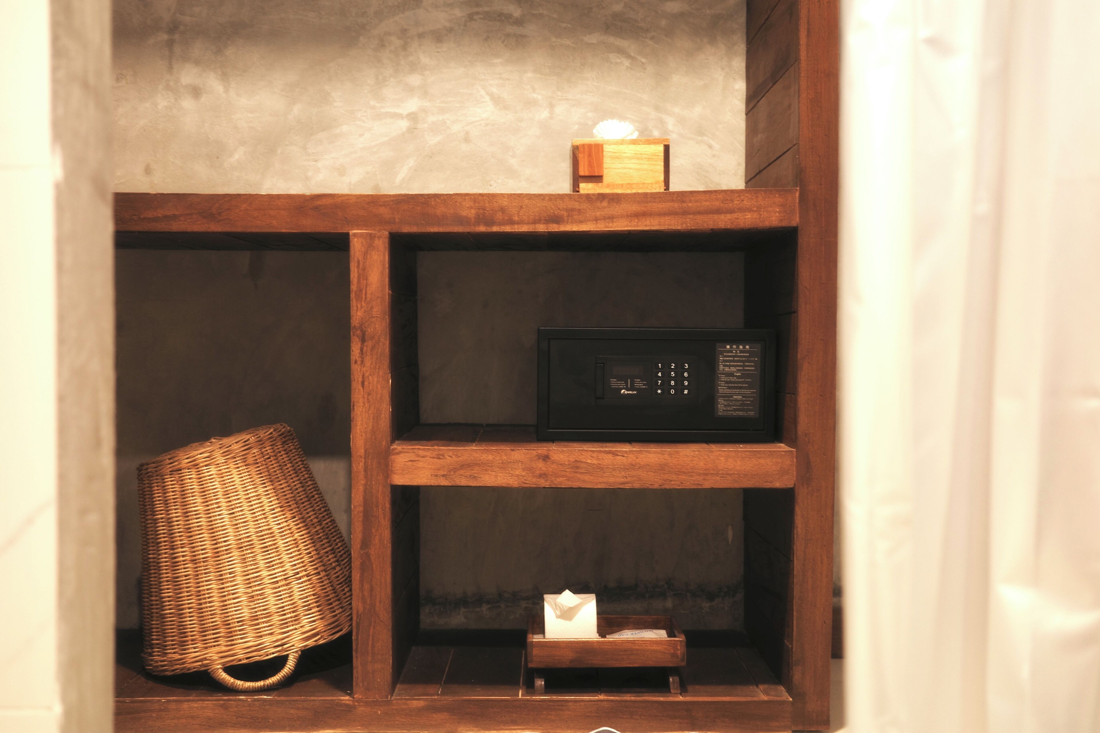 A wooden shelf unit with a microwave and a wicker basket.