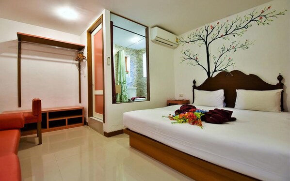 A hotel room with a bed, a chair, a window, and an air conditioning unit.