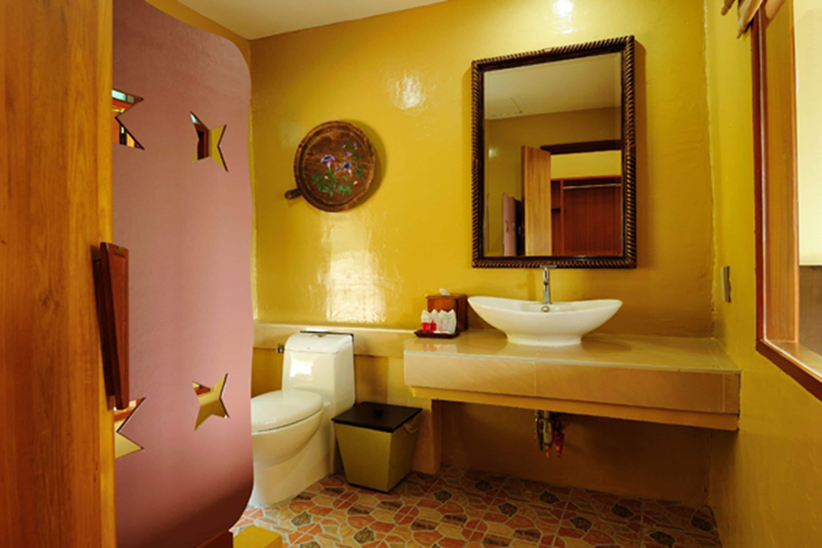 A bathroom with a toilet, sink, and mirror.