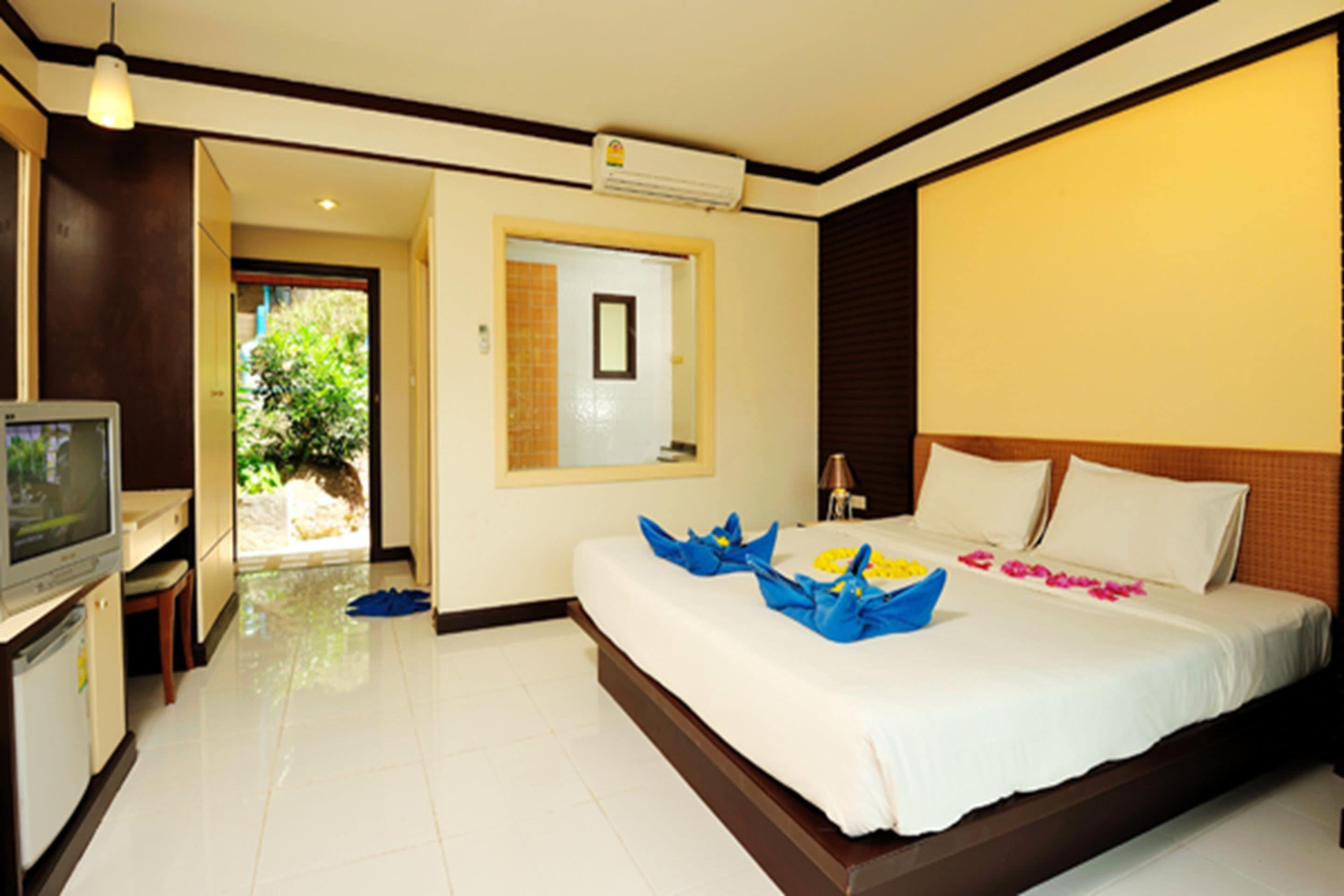 A hotel room with a bed, a TV, and a view of the outside.