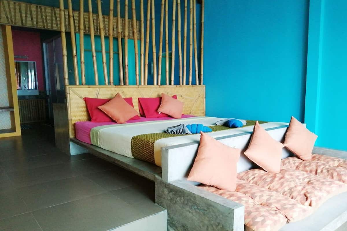 A modern hotel room with a bed, a sofa, and a bamboo partition.