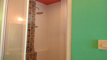 Ducha con pared de azulejos estampados y techo rojo.