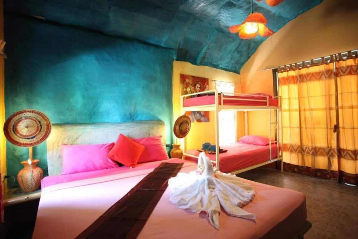A room with a bunk bed, a bedside table with a lamp, and a window with curtains.