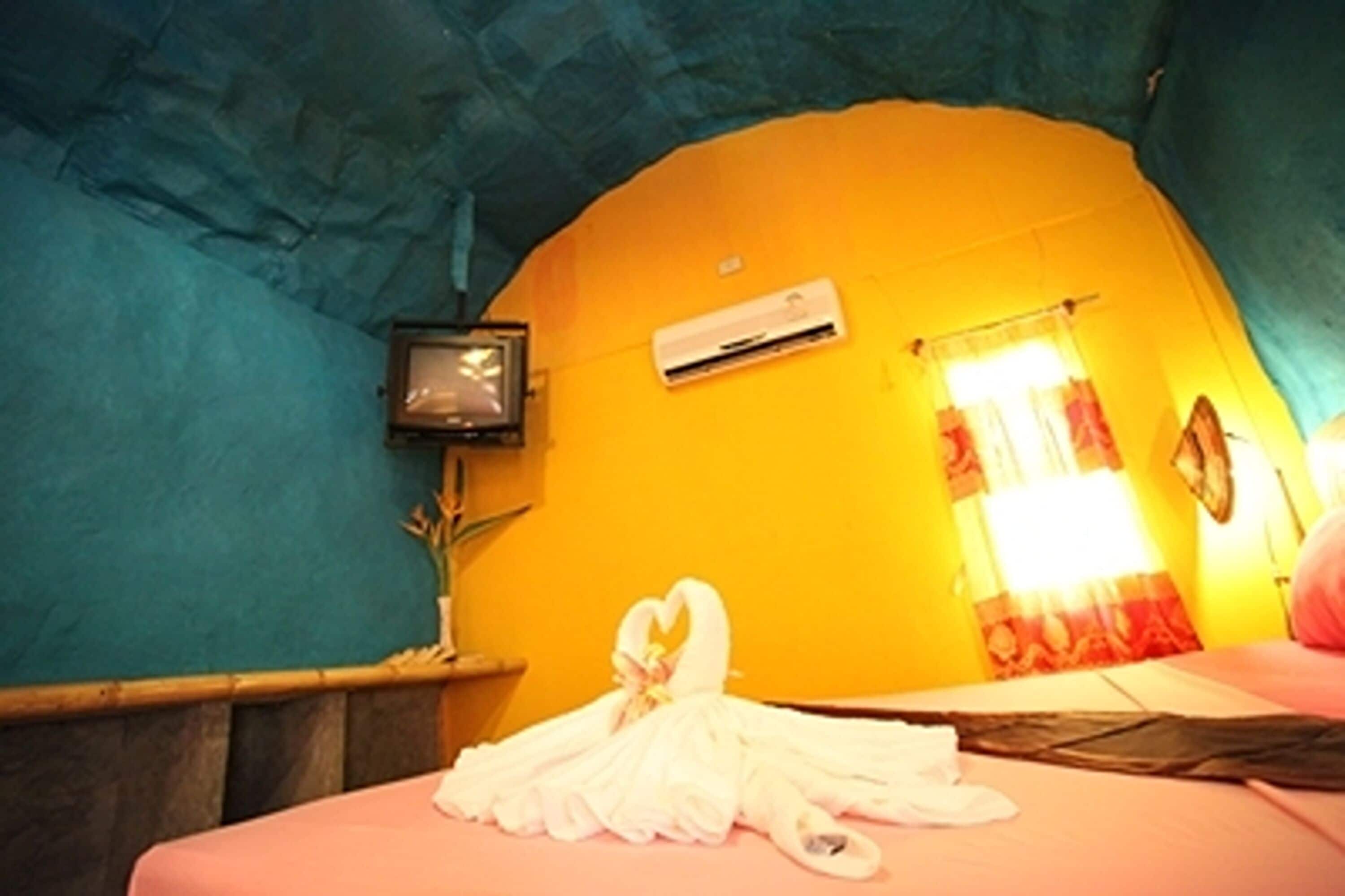 A room with a bed, a television, and an air conditioning unit on the wall.