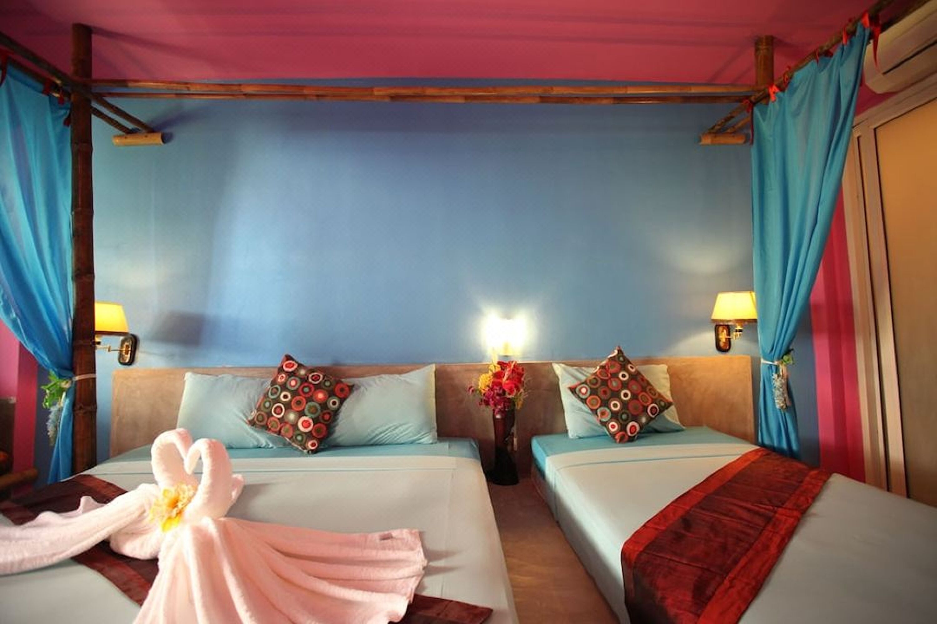 A hotel room with two beds, each with a pillow and a bedside lamp.