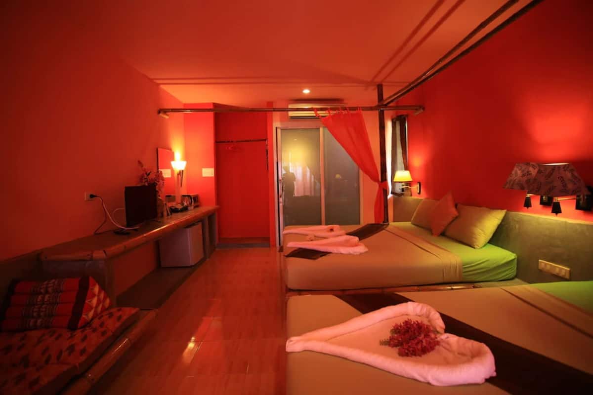 A hotel room with a bed, a sofa, a desk, and a mirror.