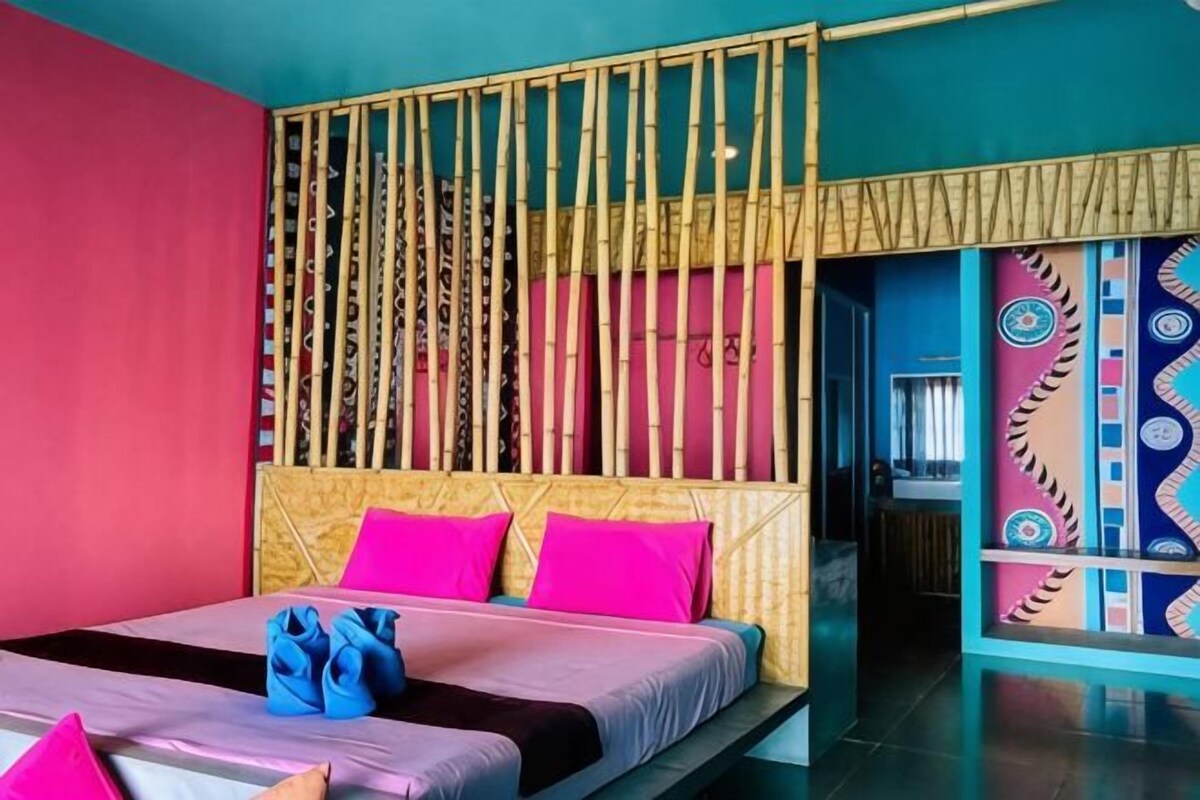 A room with a bed, a headboard, and a wall with a decorative pattern.