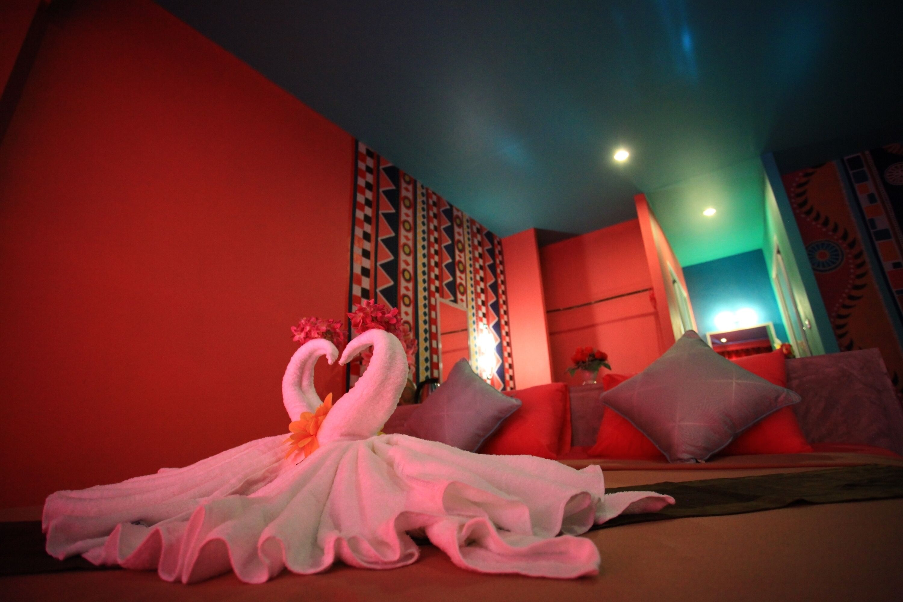 A hotel room with a bed, pillows, a wall with a geometric pattern, and a decorative swan towel.