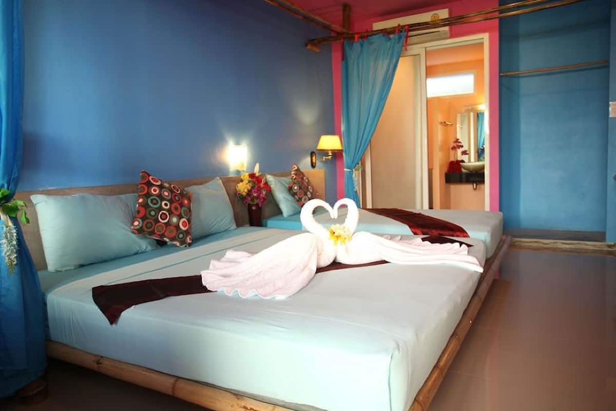 A hotel room with a bed, pillows, a nightstand, a lamp, and a floral arrangement.