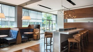 A modern bar area with seating, large windows, and a kitchen counter. - Courtyard Philadelphia South at The Navy Yard (Philadelphia)