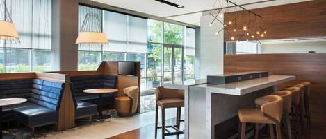 A modern bar area with seating, large windows, and a kitchen counter.