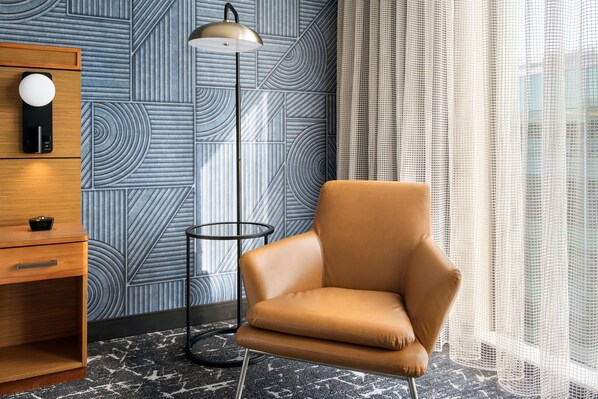 Una habitación moderna con papel tapiz estampado, un sillón de cuero, una lámpara de pie y una mesita de madera.