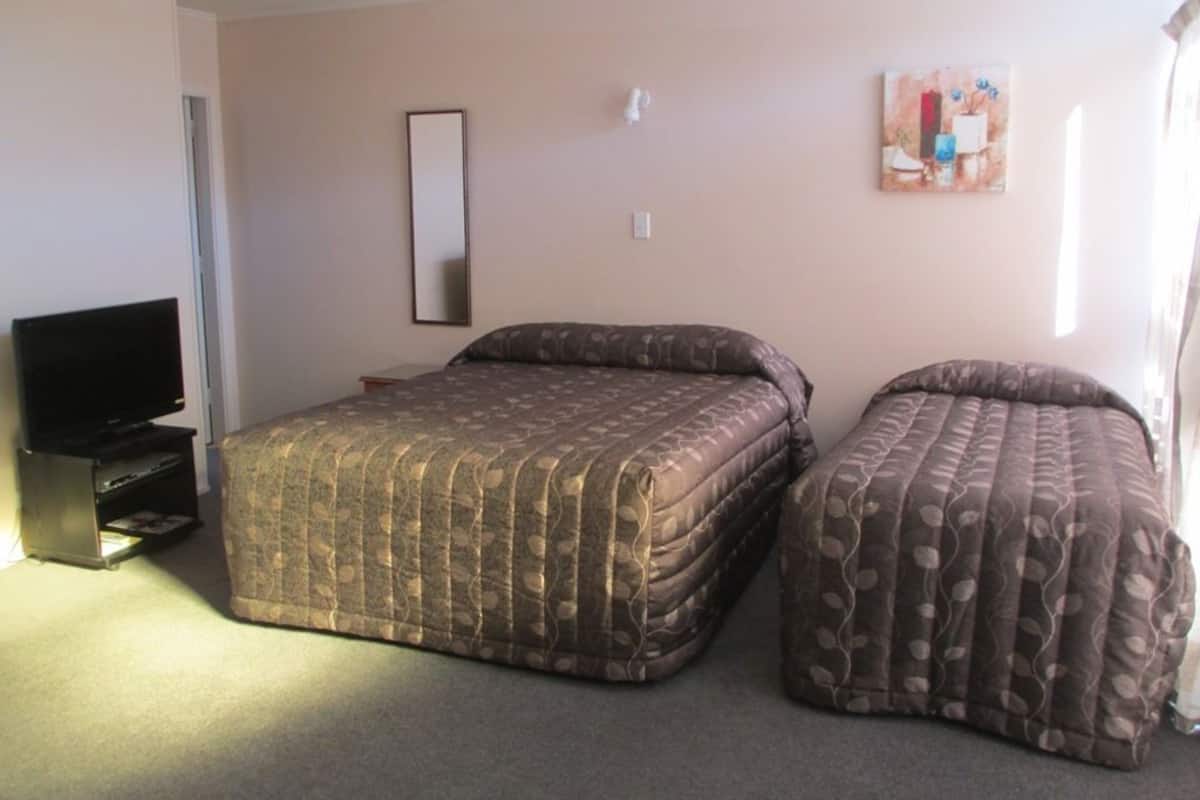 A bedroom with a bed, a TV, and a painting on the wall.