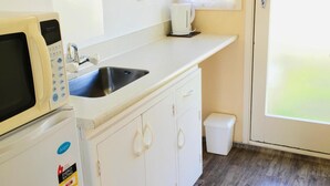 A compact kitchen with a microwave, sink, and coffee maker. - Merivale Court Motel (Christchurch)