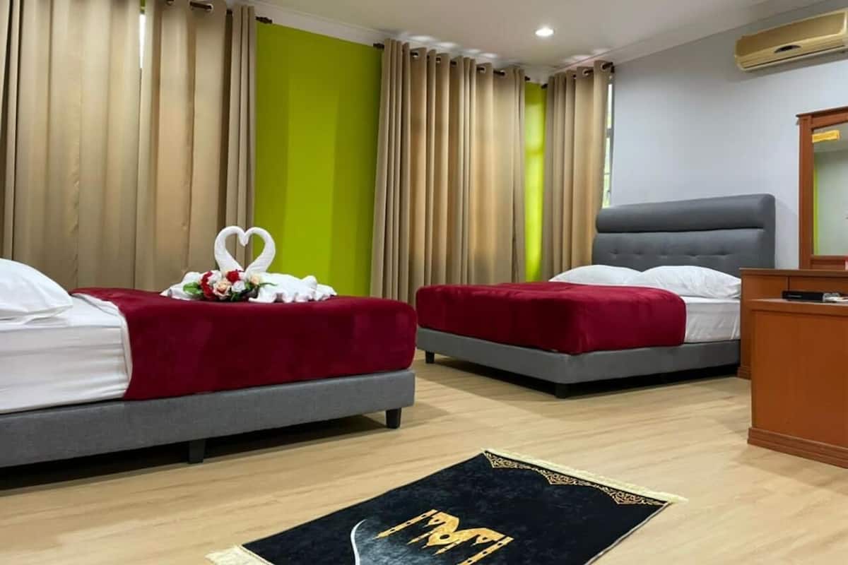 Ein Hotelzimmer mit zwei Betten, einem Schreibtisch und einem großen Spiegel.