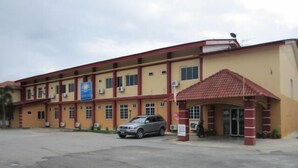 A multi-story building with a red roof and beige walls, featuring a covered entrance and a parked car. - Samudera Hotel (Kuala Besut)