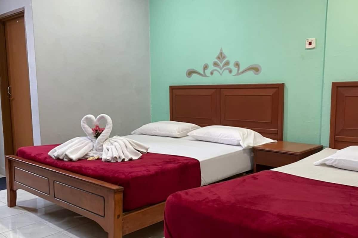 Ein Hotelzimmer mit zwei Betten, einem Holzkopfteil, einer türkisblauen Wand und einer Klimaanlage.