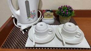 A tea set with a kettle, two cups, and a saucer, a small bowl of B&H Cameroonian Gold Blend tea, and a small potted plant. - Samudera Hotel (Kuala Besut)