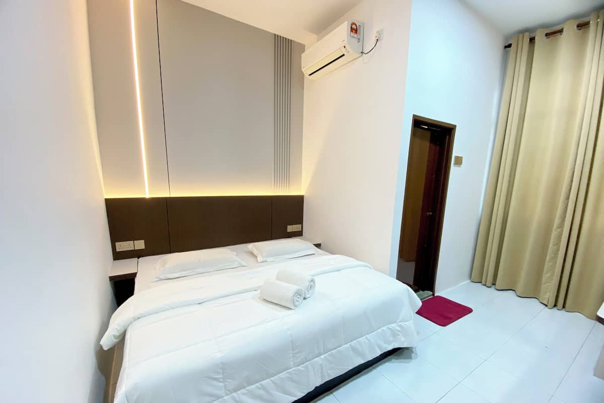 Ein Hotelzimmer mit Bett, Nachttisch, Wandairconditioner und Tür.