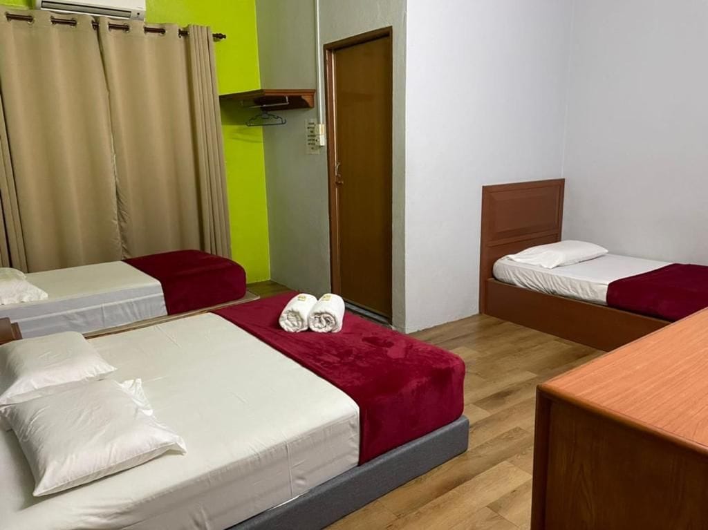 A hotel room with two beds, a wooden floor, a door, and a small table.