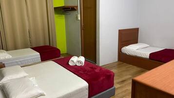 A hotel room with two beds, a wooden floor, a door, and a small table.