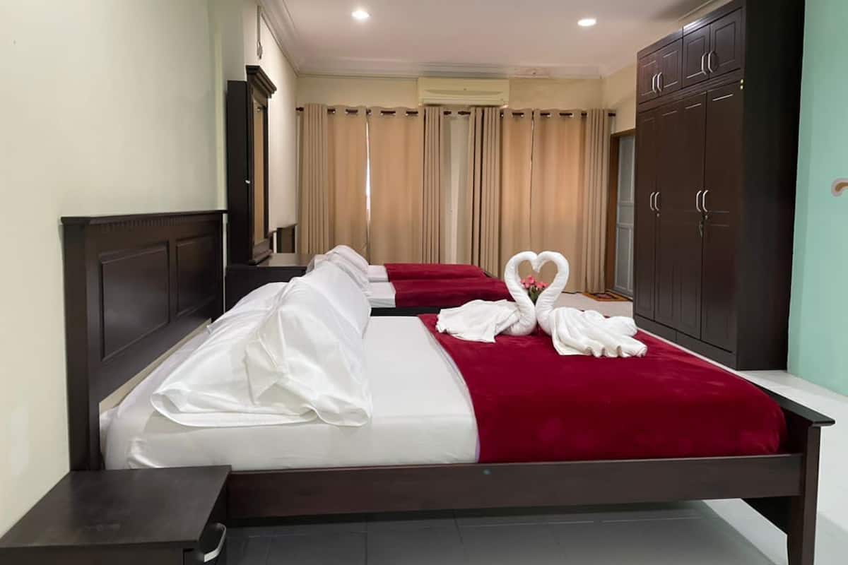 Ein Hotelzimmer mit zwei Betten, einem Kleiderschrank und einem Spiegel.