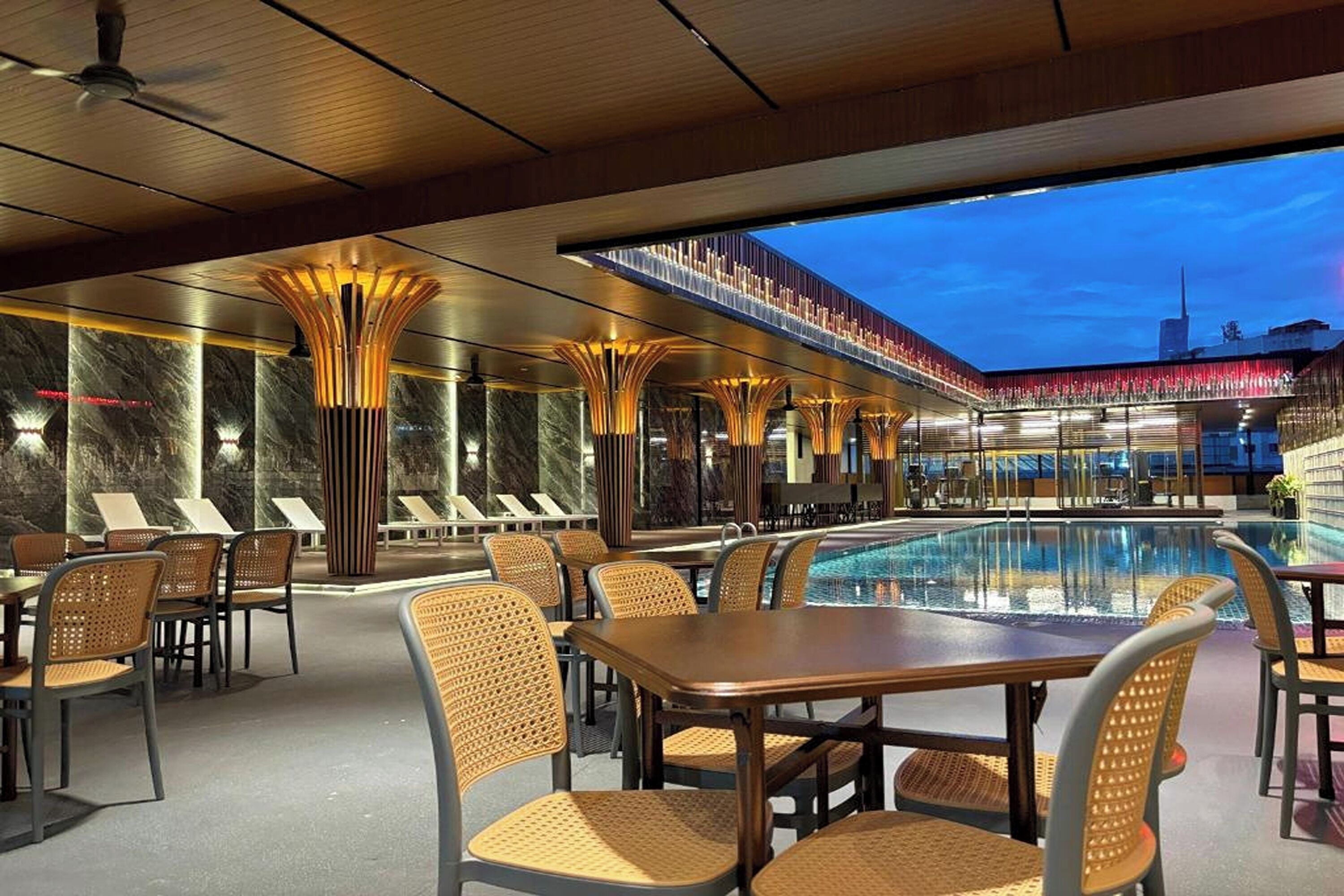 A poolside area with lounge chairs, a pool, and a modern architectural design.