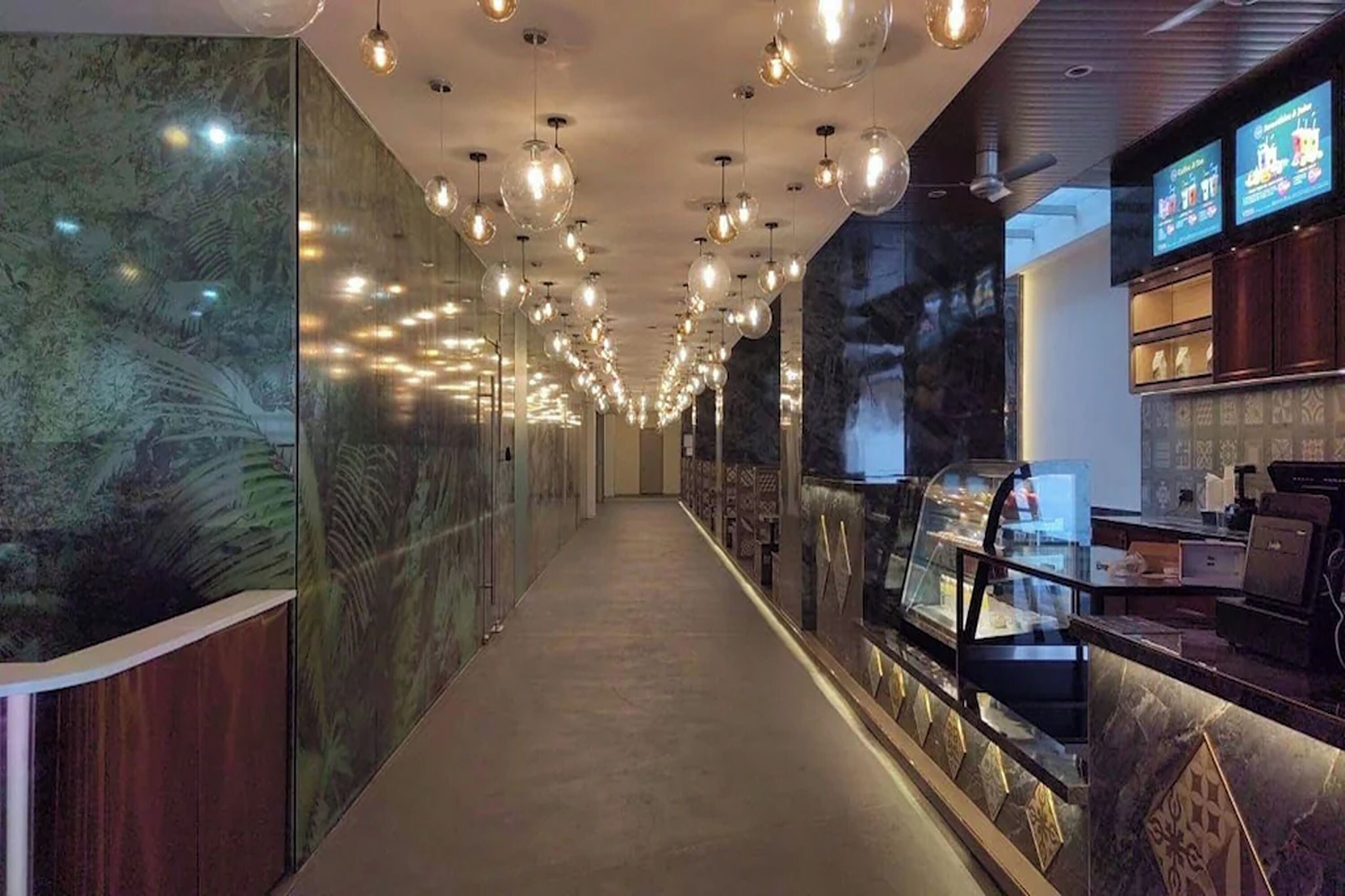 A corridor with a long counter, hanging pendant lights, and a display case.
