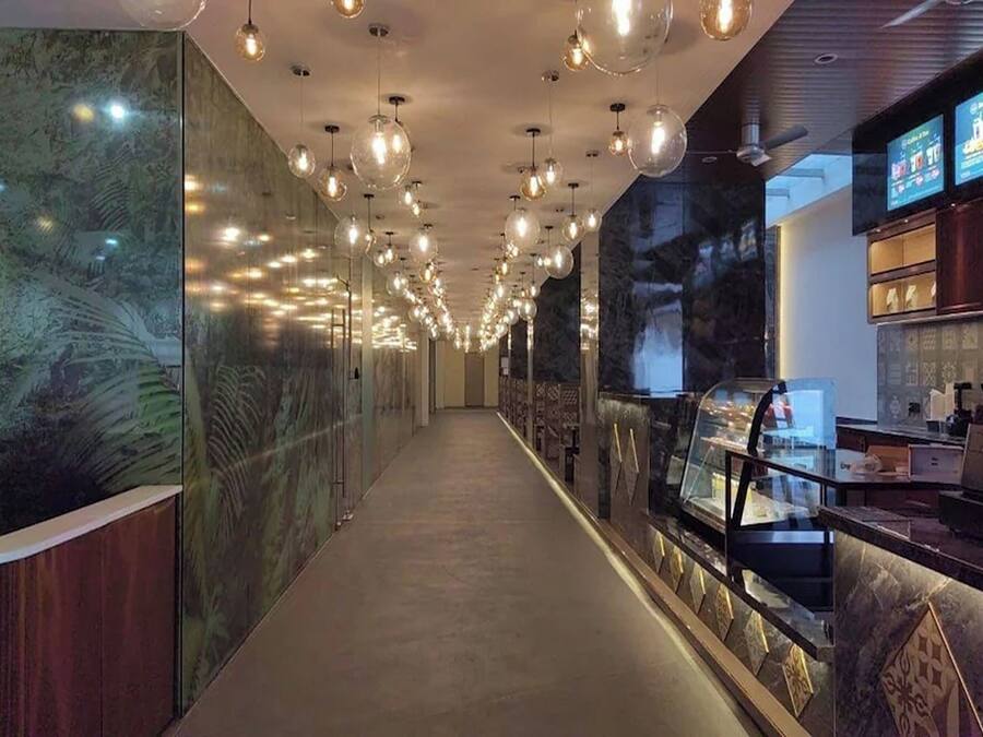 A corridor with a long counter, hanging pendant lights, and a display case.