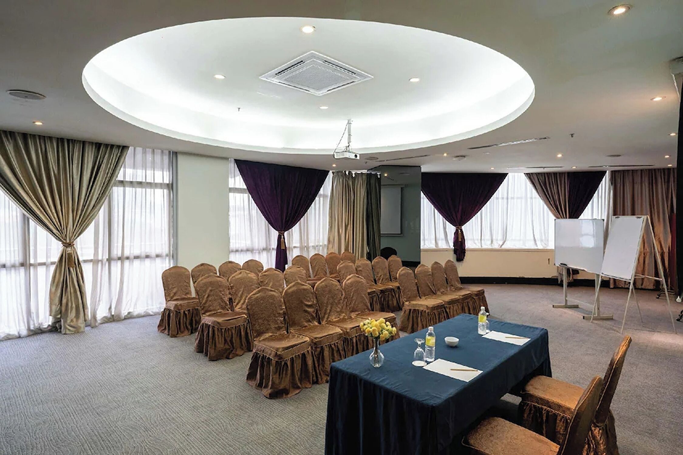 A conference room with a round table, chairs, a projector, and a whiteboard.