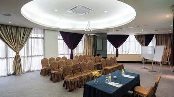 A conference room with a round table, chairs, a projector, and a whiteboard.