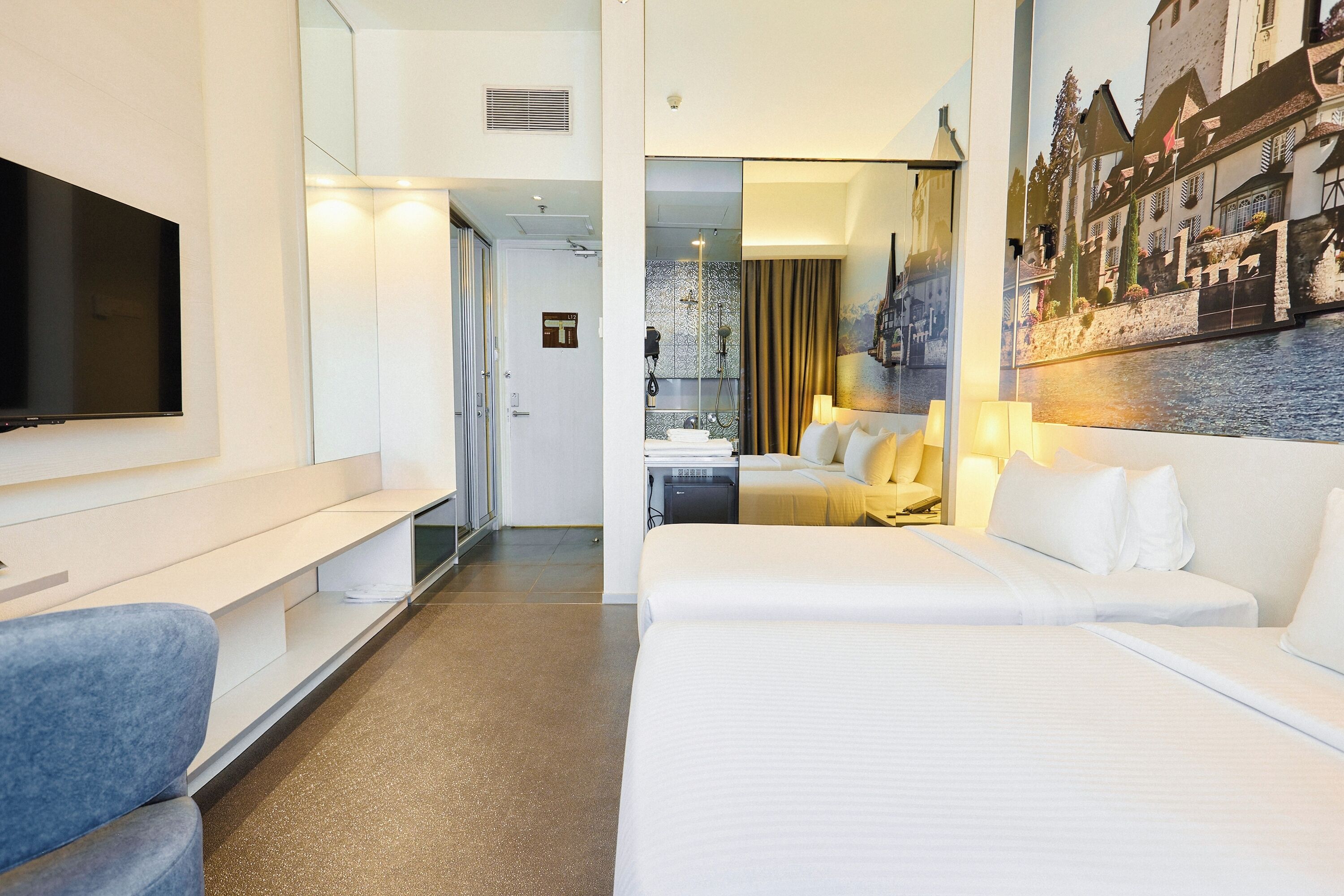 Habitación de hotel moderna con una cama grande, televisión, escritorio y baño a la vista a través de una puerta abierta.