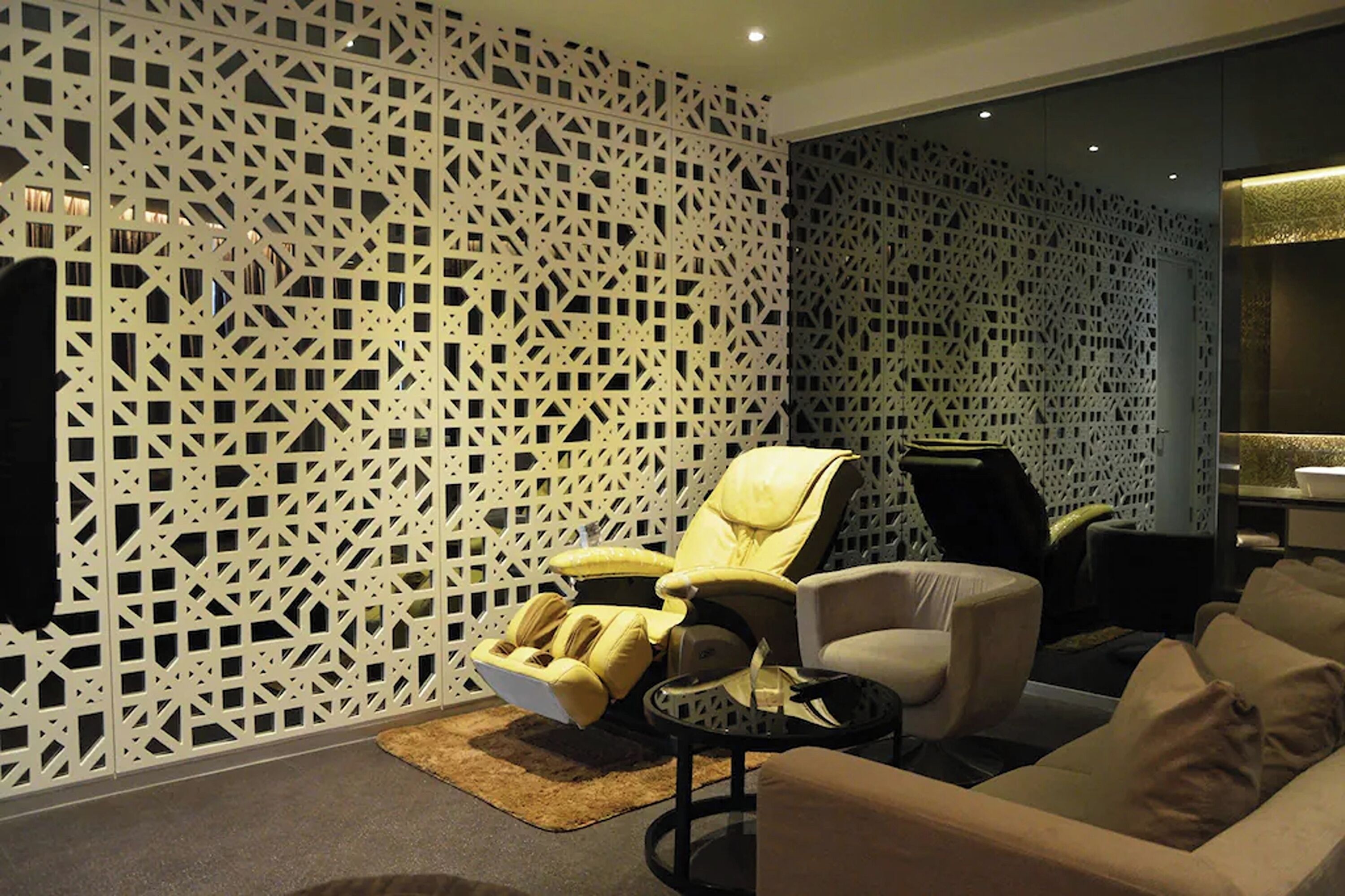 Una sala de estar moderna con un papel tapiz de diseño geométrico, un sillón reclinable, un sofá y una mesa de centro.