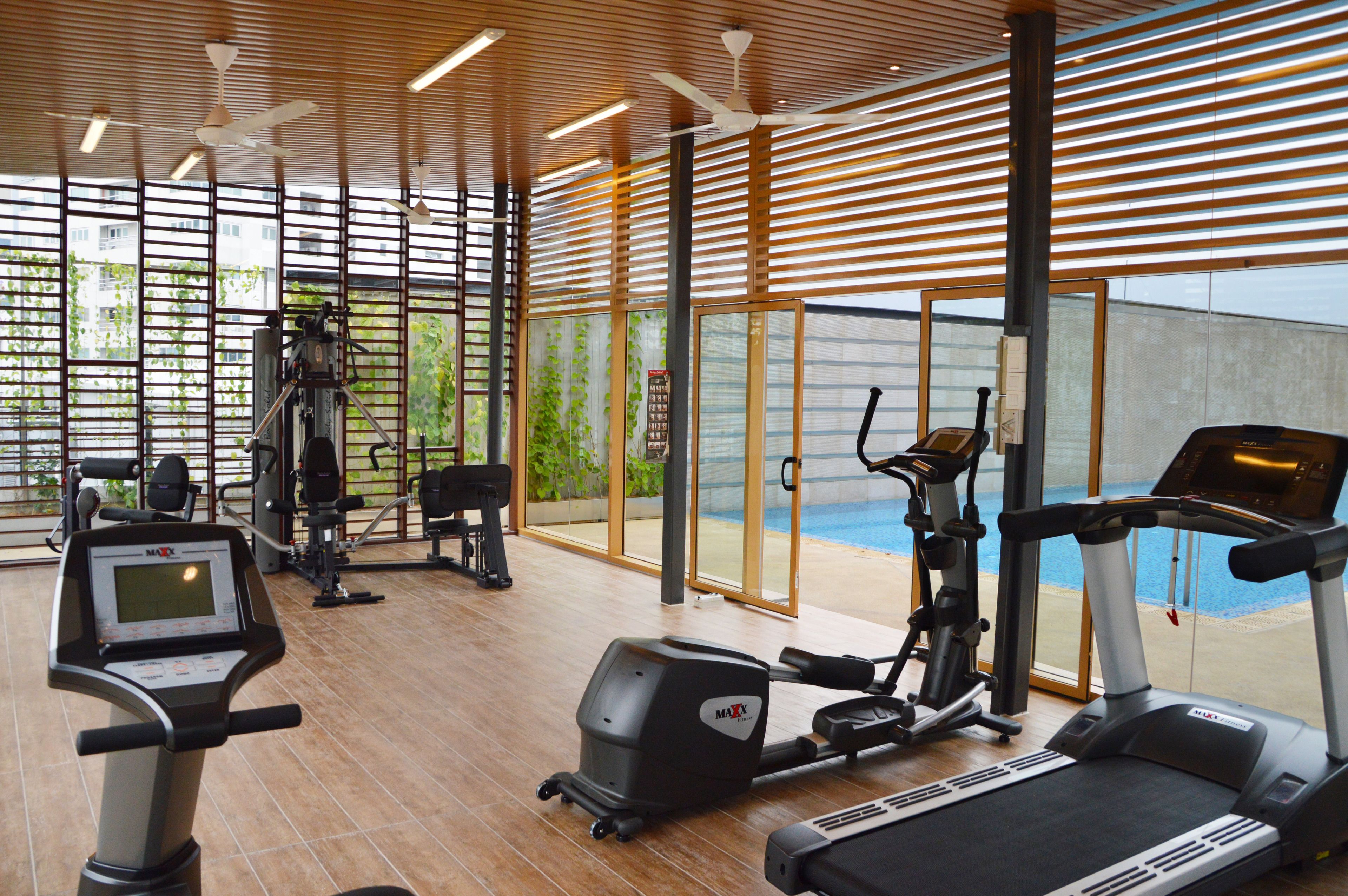 Un gimnasio moderno con diversos equipos de ejercicio, ventanas amplias y vistas al exterior.