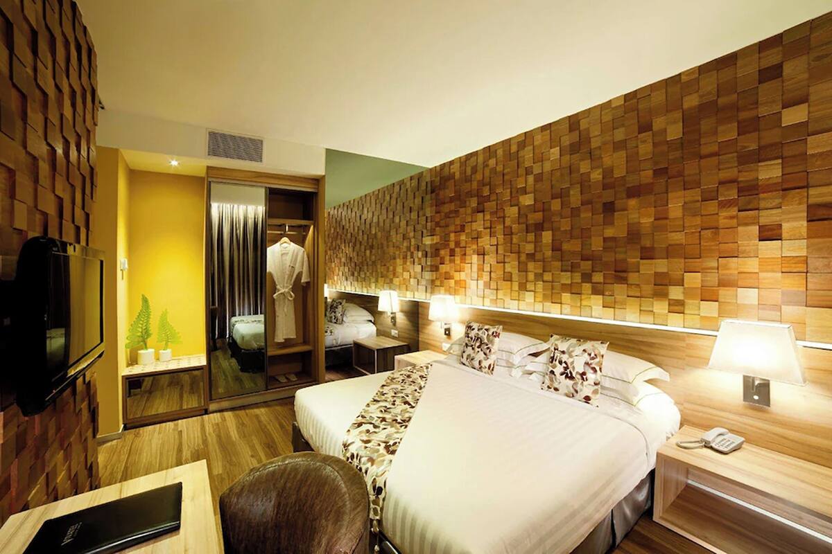 Ein Hotelzimmer mit einem großen Bett, einem Nachttisch mit Lampe, einem Spiegel und einer Holzvertäfelung.