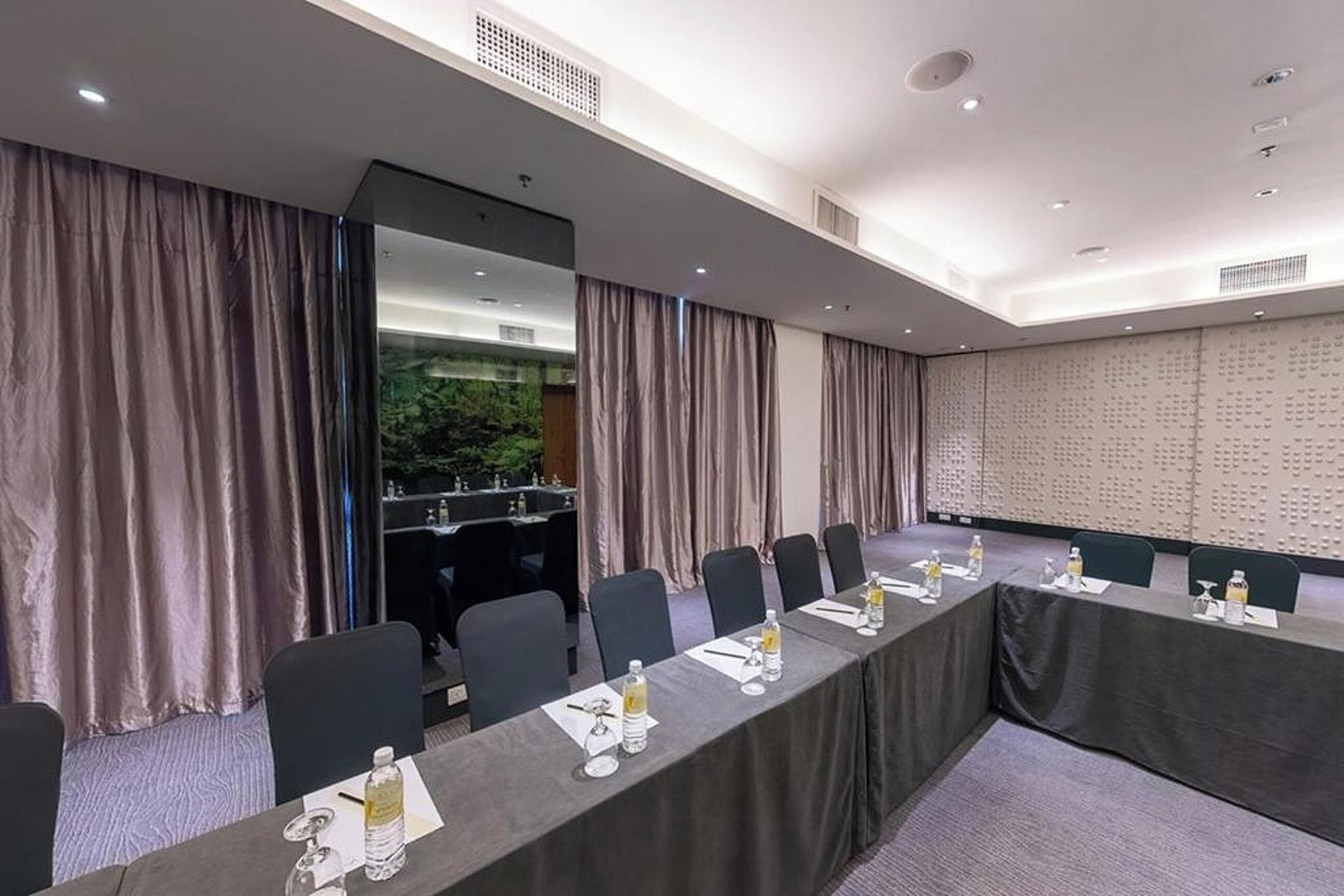 A conference room with a long table, chairs, and a backdrop with a pattern.