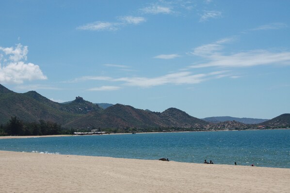 A beach with mountains in the background and a clear sky.