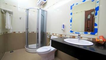 A bathroom with a glass-enclosed shower, a white toilet, a sink with a mirror, and a towel rack.