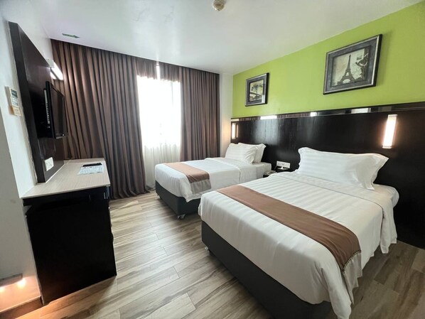 Habitación de hotel con dos camas, un escritorio y un televisor.