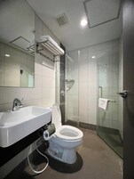 A modern bathroom with a white sink, toilet, and glass-enclosed shower.