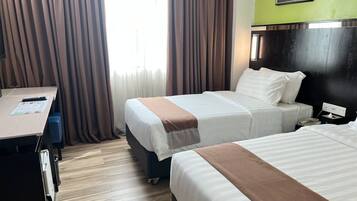 Quarto de hotel com duas camas, uma escrivaninha e uma cadeira.