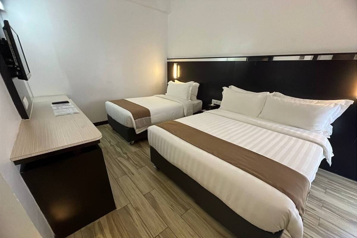A hotel room with two beds, a desk, and a chair.