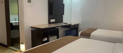 Habitación de hotel con dos camas, un escritorio, un televisor de pantalla plana y un espejo.