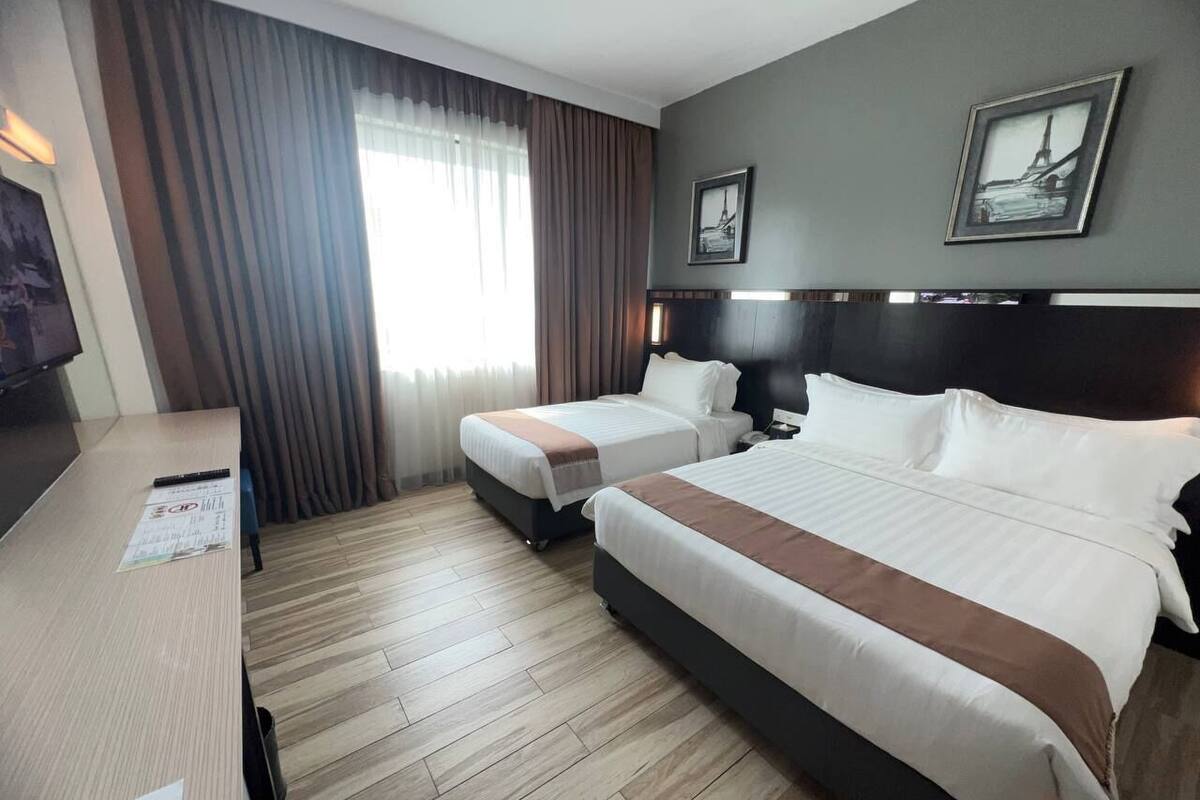 A hotel room with two beds, a desk, and a TV.
